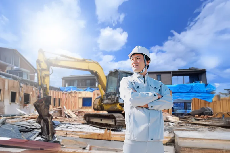 解体工事現場に立つ作業員と重機